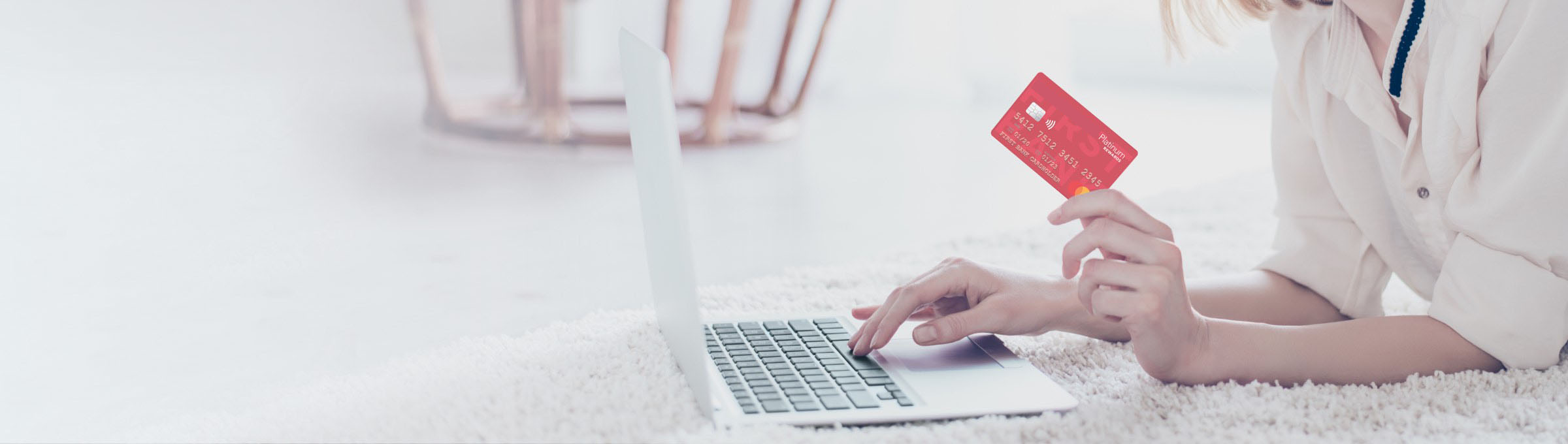 a woman holding her lite Valley Credit Union Platinum Rewards card while on the computer.